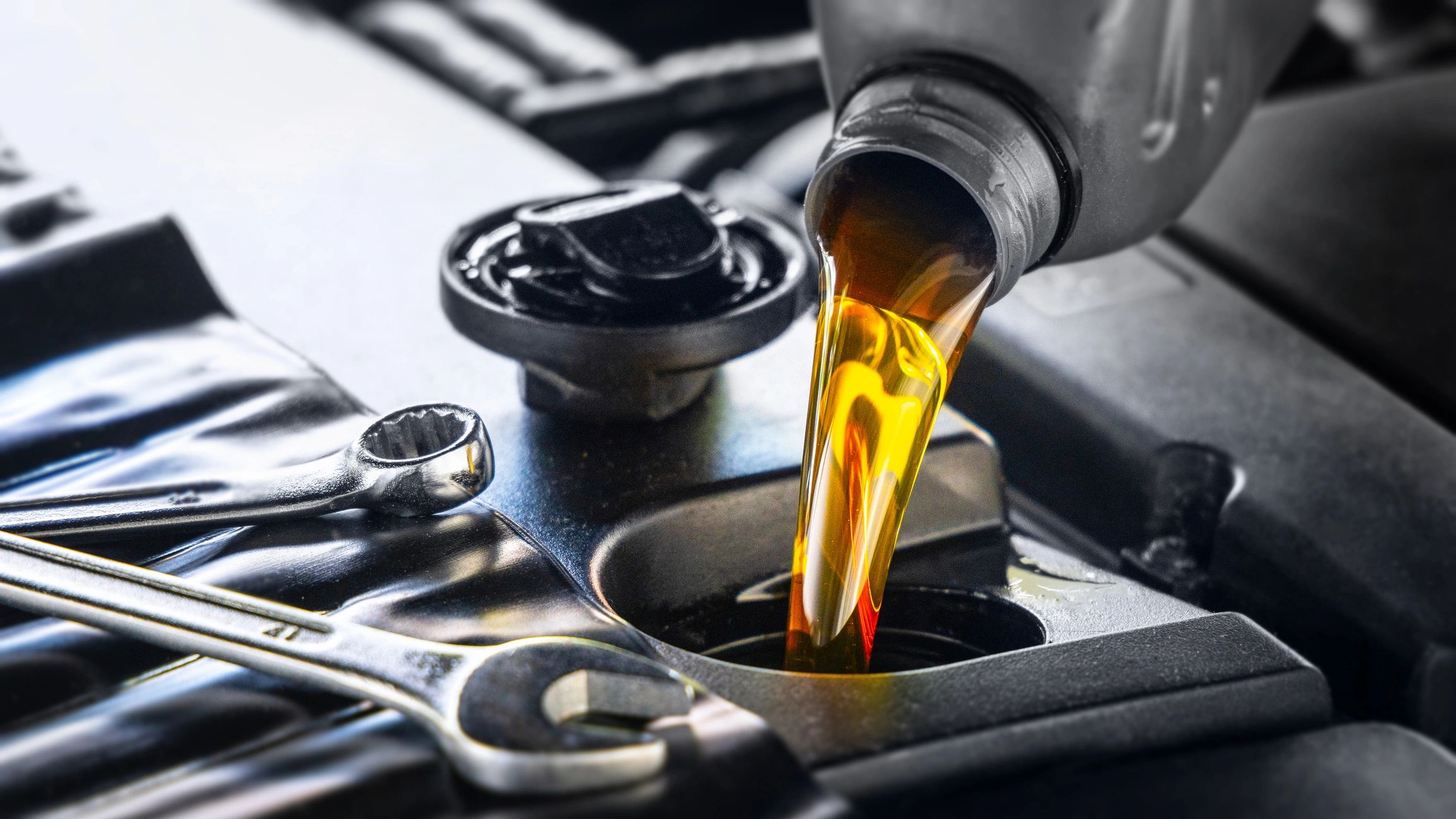 Technician performing an oil service on a vehicle engine