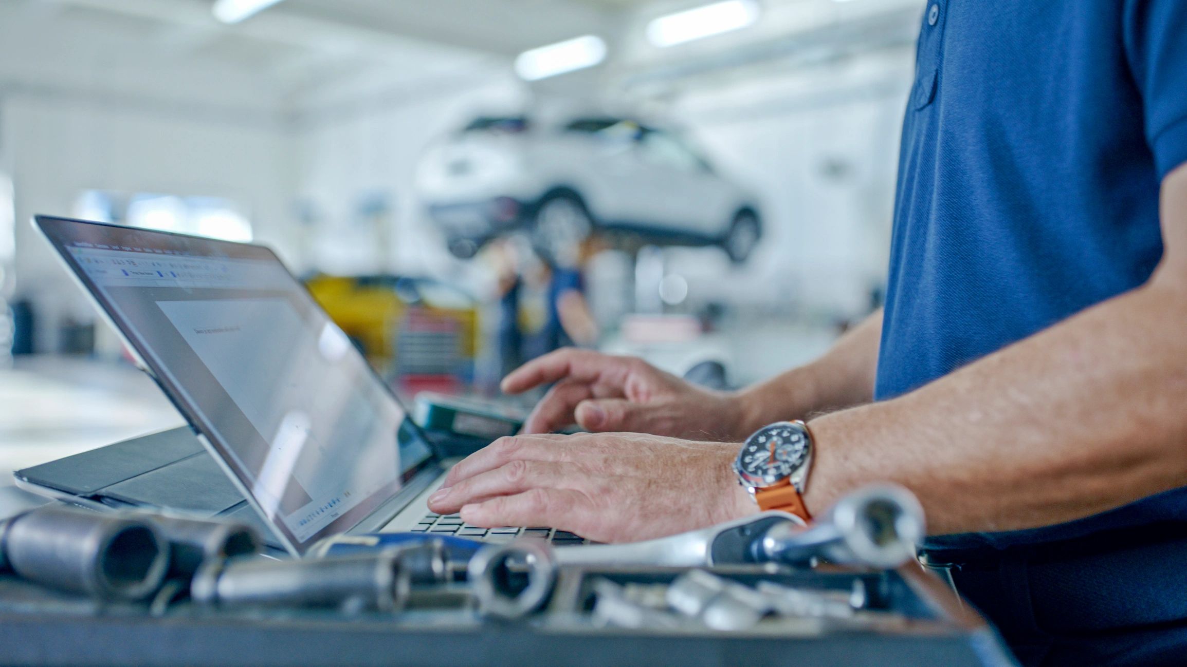 Service manager reviewing repair information on a laptop in an auto shop